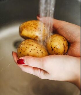 Hands holding potatoes under water